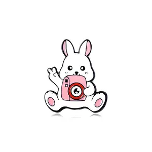 Cute white rabbit enamel pin holding a pink camera, creative cartoon alloy brooch accessory