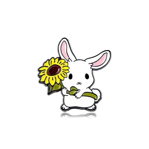 Detail of cute white bunny enamel pin holding a sunflower in polished alloy