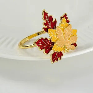 Close-up of golden maple leaf napkin ring with autumn enamel colors on white porcelain