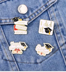 Detailed view of four graduation enamel pins on denim with Happy Graduation lettering
