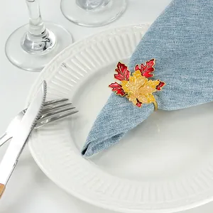 Close-up of enamel maple leaf napkin ring with golden band on blue fabric napkin