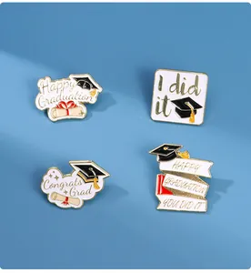 Detailed view of four enamel graduation pins featuring caps and scrolls on blue background