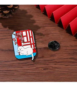 Close-up of white cat enamel pin on red window lattice over dark wood background