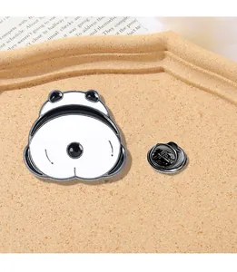 Close-up of cute cartoon frog butt enamel pin with black clutch back on a tray
