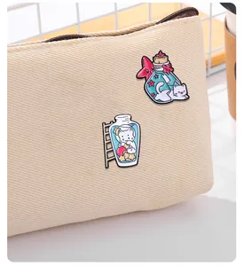 Détail de deux épingles en émail de chats mignons dans des bocaux sur un sac en toile