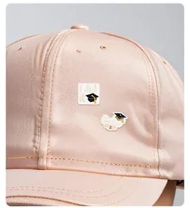 Close-up of graduation enamel pins with Congrats Grad text on a pink satin cap
