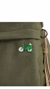 Close-up of a green vintage bicycle enamel brooch with bird on an olive canvas bag