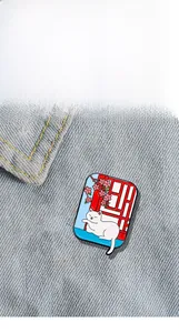 Detail of a white cat enamel pin on a red Chinese window with pink flowers on denim fabric
