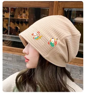 Détail de la texture du bonnet en maille beige avec broches de chat volant de Dunhuang