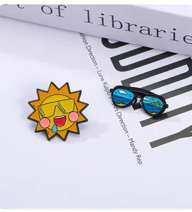 Détail des broches en émail soleil et lunettes de plage sur un fond décoratif moderne