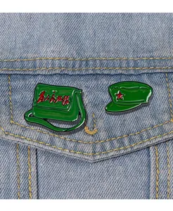 Detail of vintage green enamel pins with red star and Chinese text on denim jacket