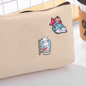 Lot de pins en émail chats kawaii dans des bocaux sur un sac en toile beige