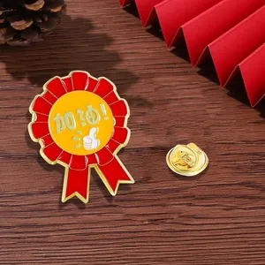 Makroaufnahme einer rot-goldenen Emaille-Belohnungsnadel mit Daumen hoch und Text