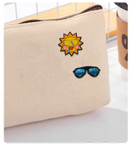 Vue détaillée de pin's émaillés soleil cartoon et lunettes de plage sur un sac