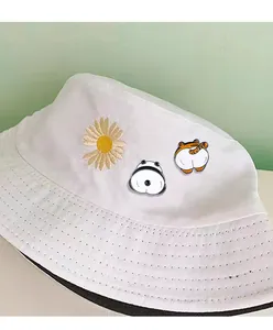 Detailed view of enamel badges featuring cartoon panda and tiger butts on a white bucket hat