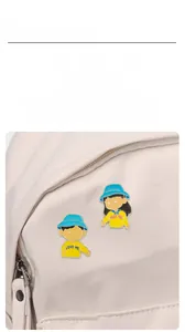 Close-up of cute cartoon couple enamel pins on canvas bag with Love Me and Hug Me text