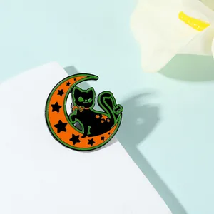 Détail d'une broche en émail représentant un chat noir sur un croissant orange