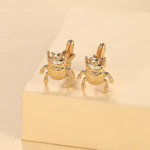 Macro view of gold beetle-shaped shirt cufflinks with polished metallic finish and textures