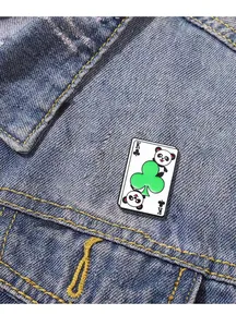 Detail of creative panda king of clubs enamel pin on blue denim fabric texture