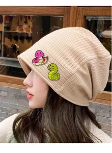 Texture détaillée du bonnet en maille beige avec écussons de serpent de dessin animé