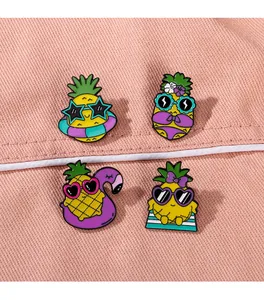 Détail de quatre broches en émail d'ananas mignonnes sur un fond en tissu denim rose