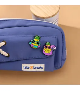 Détail du sac en toile bleue avec des pins ananas mignons et étiquette take breaks