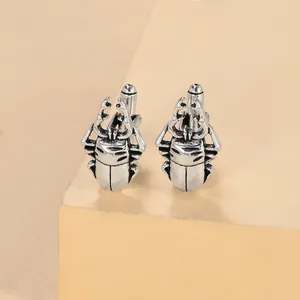 Detail of stag beetle cufflinks in antique silver alloy with fine textured metal carvings