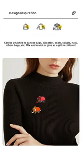 Détail de broches éléphant aux motifs ethniques épinglées sur un pull noir en maille