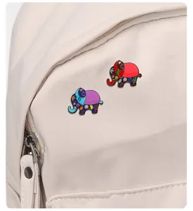 Détail de broches émaillées éléphant colorées fixées sur un sac en toile blanc