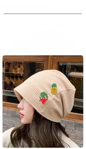 Gros plan sur les pins fraise et ananas en émail sur un bonnet en maille beige