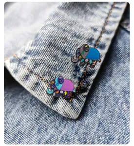 Gros plan de deux broches éléphants en émail de style ethnique sur un col en jean