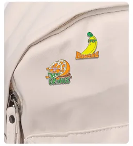 Gros plan de pin's émaillés mignons orange et banane sur un sac à dos en toile
