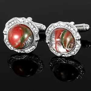 Macro shot of silver cufflinks with red and green swirl glass center and inlaid rhinestones