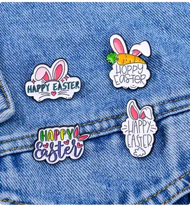 Macro shot of Easter enamel pins with rabbit and carrot designs on denim fabric