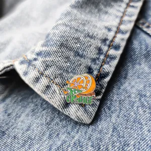 Broche en émail orange cartoon avec texte ORANGE sur une veste en jean bleue