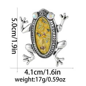 Detailansicht einer Vintage-Froschbrosche in Silber mit gelber Muscheleinlage und Strass