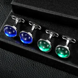 Macro shot of blue and green round gemstone cufflinks in a black leather display box