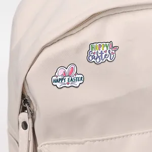 Easter bunny enamel pins with Happy Easter lettering on beige canvas backpack