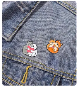 Dettaglio di spille in smalto con gatti e volpi su tasca di giacca di denim blu