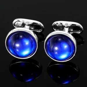 Classic silver round cufflinks with oval blue opal stone inlay on black reflective surface