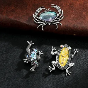 Makroaufnahme von Vintage-Tierbroschen in Silber mit Perlmutt-Inlays auf Leder