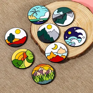 Detalle de 7 pines esmaltados con paisajes de playa, montaña y bosque sobre madera