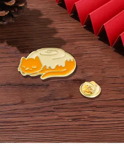 Detail view of cute orange cat enamel pin with butterfly clasp on a wooden desk