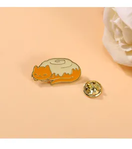 Close-up of a cute cat enamel pin shaped like a cinnamon roll with a gold butterfly clutch