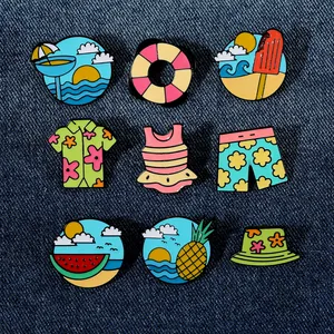 Macro detail of nine colorful enamel beach theme pins on blue denim fabric background