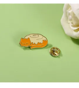 Detail of cute cat cinnamon roll enamel pin with gold butterfly clutch on green background