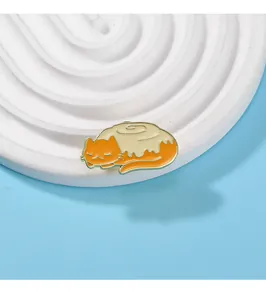 Detailed view of a cute sleeping orange tabby cat enamel pin on a white platform