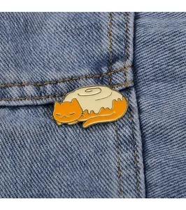 Macro shot of a cute orange cat cinnamon roll enamel pin on blue denim fabric