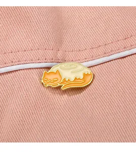 Detail of cute cat cinnamon roll enamel pin showing gold plating and smooth dripping oil finish