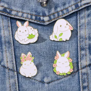 Set of four cute white rabbit enamel pins on denim jacket featuring cartoon bunny designs